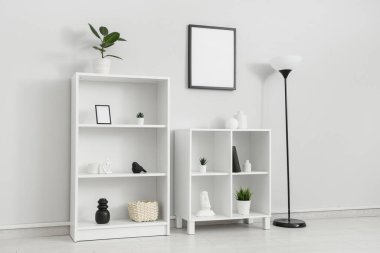 Raflar ve zemin lambaları beyaz duvarın yanında.