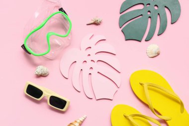 Dalış maskeli kağıt tropikal yapraklar, parmak arası terlikler ve pembe arka planda deniz kabukları. Yaz konsepti