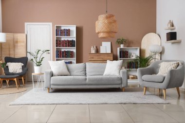 Modern oturma odasının içinde kitaplık, rahat kanepe ve koltuk var.