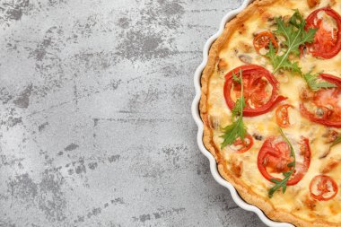 Gri arka planda roka yapraklı lezzetli domatesli tart, yakın plan.