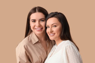 Kahverengi arka planda genç kızı olan güzel olgun bir kadın. Anneler Günü kutlaması