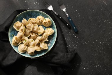 Siyah arkaplanda yeşil soğanlı lezzetli haşlanmış hamur köfteleri.