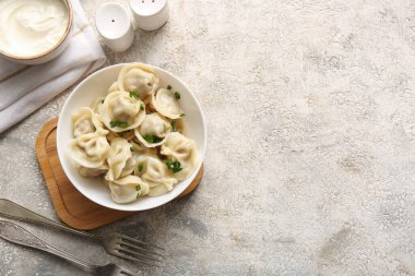 Bir kase lezzetli haşlanmış hamur köftesi, yeşil soğanlı ve ekşi kremalı.