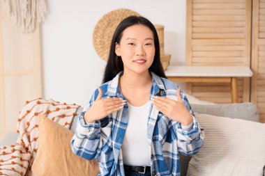 Dilsiz Asyalı kadın evde işaret dili kullanıyor.