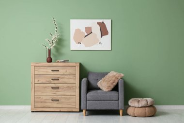 Gri koltuklu, puflu ve ağaç dallı ahşap şifoniyerli şık bir oturma odası.