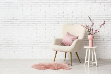 Beyaz koltuklu ve sehpanın üzerinde çiçek açan ağaç dalları olan şık bir oturma odası.