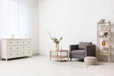 Gri koltuğu ve kahve masasının üzerinde çiçek açan ağaç dalları olan şık bir oturma odası.