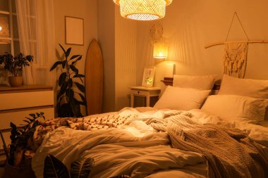 Yatak odasının içinde sörf tahtası, parlayan lambalar ve geceleri masa var.