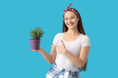 Güzel genç bir kadın, mavi arka planda lavanta çiçekleri olan otu işaret ediyor.