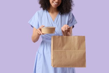 Leylak kaplamalı kese kağıdı olan genç bir kadın. Yemek dağıtım servisi.