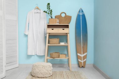 Masası, perdesi, bornozu ve sörf tahtası olan şık bir oda.