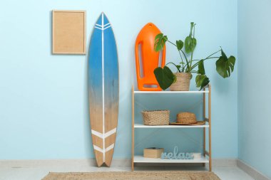 Rafların, yüzme tahtasının, tropikal bitki ve sörf tahtasının bulunduğu şık bir oda.
