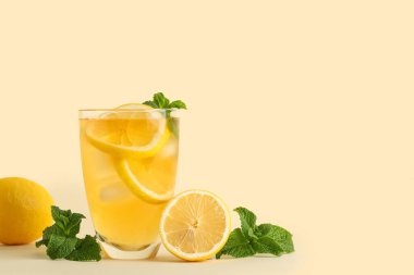 Bej arkaplanlı bir bardak limonlu buzlu çay.