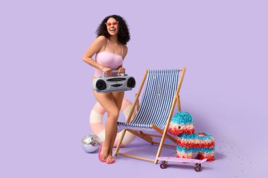 Leylak arka planında müzik çalar ve plaj aksesuarları olan genç bir Afro-Amerikalı kadın. Yaz partisi