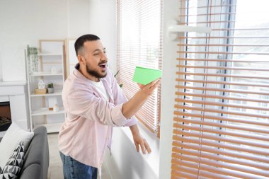Ofiste pencerenin yanında kağıt uçağı olan genç bir adam.