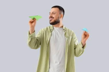 Hafif arka planda kağıt uçaklar olan genç bir adam.