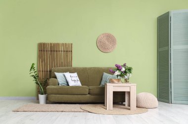 Ahşap sehpa ve kanepe oturma odasının iç tarafındaki yeşil duvarın yanında.