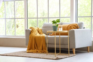 Oturma odasının penceresinin yanındaki sehpa ve kanepe.