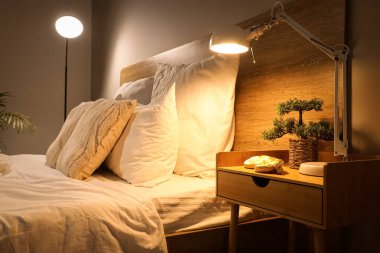 Masanın üzerinde bonsai ağacıyla parlayan lamba.