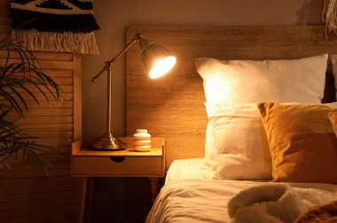 Karanlık yatak odasındaki masada parlayan lamba.