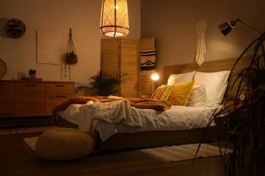 Koyu renk yatak odasının içinde katlanan ekran, bitkiler ve parlayan lambalar.