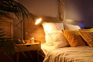 Karanlık yatak odasındaki masada parlayan lamba.