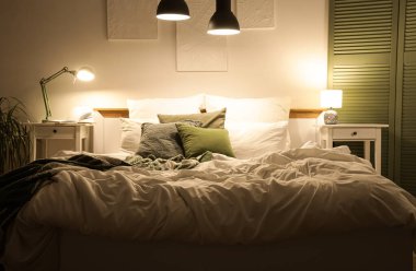 Yatak odasının içinde masalar ve geceleri parlayan lambalar.