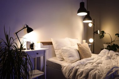 Masası ve parlak lambaları olan karanlık yatak odasının içi.