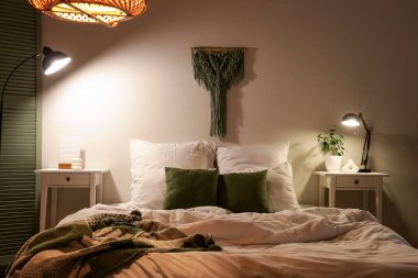 Yatak odasının içinde masalar ve geceleri parlayan lambalar.