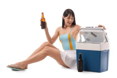 Portatif buzdolabı ve beyaz arka planda soğuk bira şişesi olan genç bir kadın.
