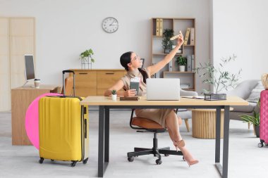 Genç iş kadını ofiste tatil hayali kuruyor.