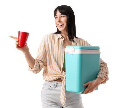 Portatif buzdolabı ve bir fincan soğuk içecekle beyaz arka planda bir şey gösteren genç bir kadın.