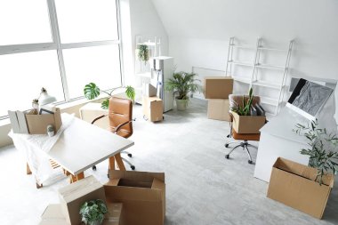 Taşındığı gün yeni ofiste içinde eşyalar ve mobilyalar olan kutular.