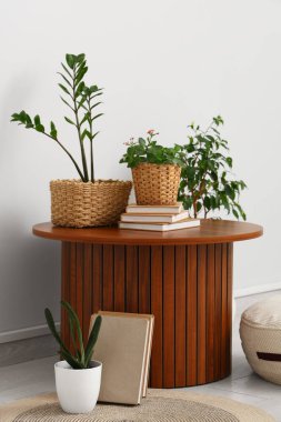 Kitaplı masa ve aydınlık odada yeşil bitkiler.