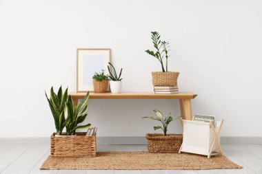 Masa ve hasır sepetler. Odada ışık duvarı yakınında bitkiler var.