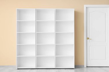 Bej duvarın yanındaki boş kitaplık.