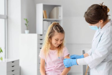 Klinikte aşıdan sonra doktordan yama alan tatlı küçük kız.