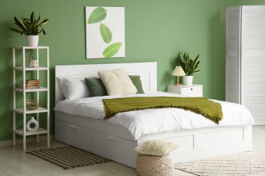 İçinde yatak, raf ünitesi ve Sansevieria bitkileri olan bir oda.