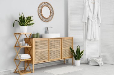 Lavabo, katlanan ekran ve Sansevieria bitkileriyle dolu bir banyo.