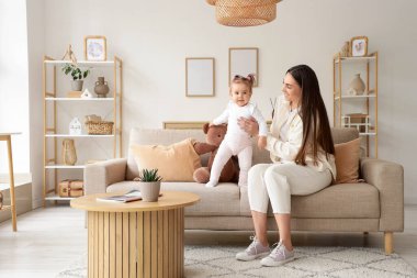 Anne ve bebeği evdeki kanepede oturuyor.