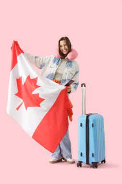Kanada bayrağı ve pembe arka planda valizi olan bir kadın turist.