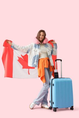 Kanada bayrağı ve pembe arka planda valizi olan bir kadın turist.