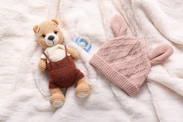 Oyuncak ayı, bebek şapkası ve emzik açık ekose üzerinde