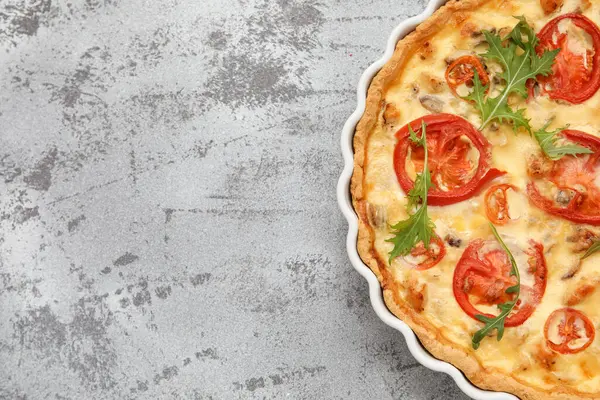 Gri arka planda roka yapraklı lezzetli domatesli tart, yakın plan.