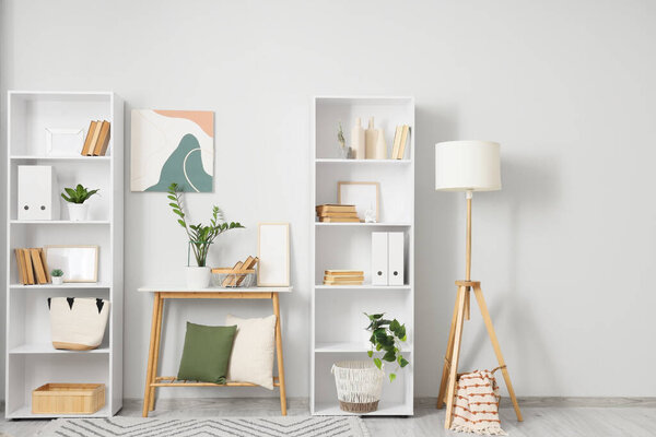 Interior of light room with bookshelves, table and lamp