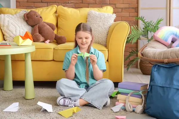 Evdeki halıda kağıt uçakla oturan tatlı kız.