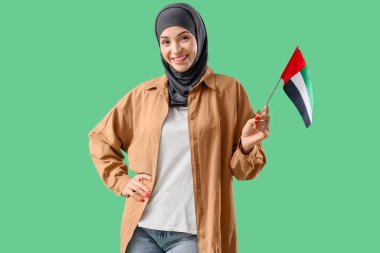 Yeşil arka planda BAE bayrağı olan genç Müslüman kadın.