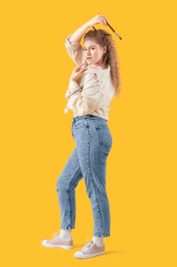 Sarı arka planda boya fırçası olan kadın sanatçı