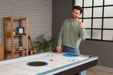 Mutlu genç adam evde hokey oynuyor.