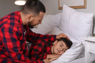 Babası yatak odasında uzanmış sevimli küçük bir çocuk.